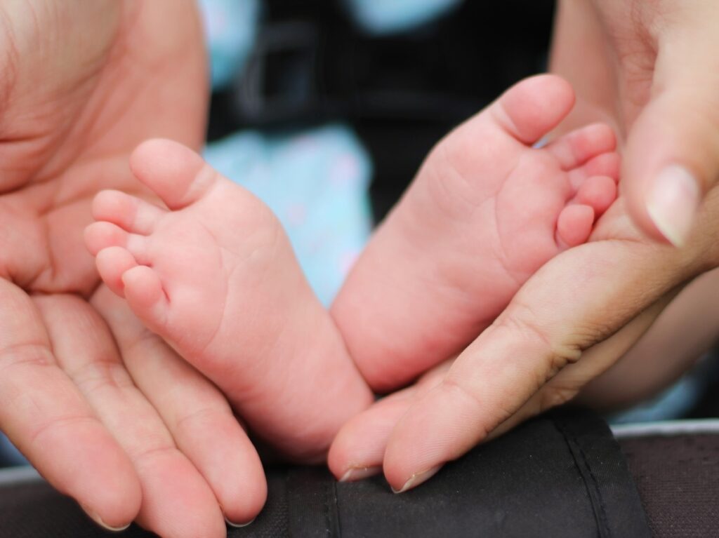 Foto de pies de bebé sostenidos por manos de una mujer.