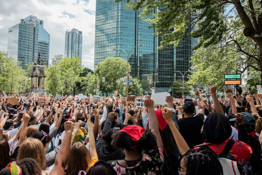 Foto de una manifestación que se realiza en la calle y reúne a centenares de personas que empuñan en alto se mano derecha.