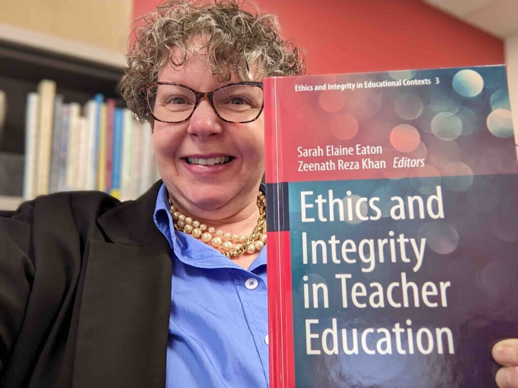 Foto de la académica Sara Elaine Eaton mostrando el libro Ethics and Integrity in Teacher Education.