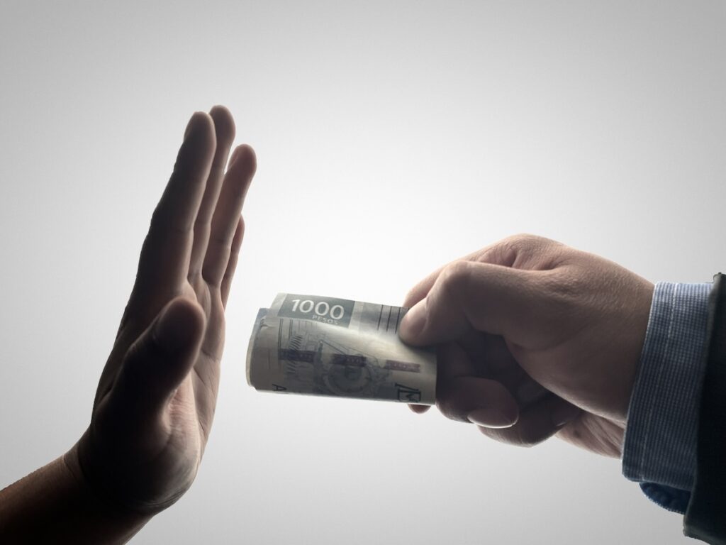 Foto de una mano entregando dinero a otra mano.