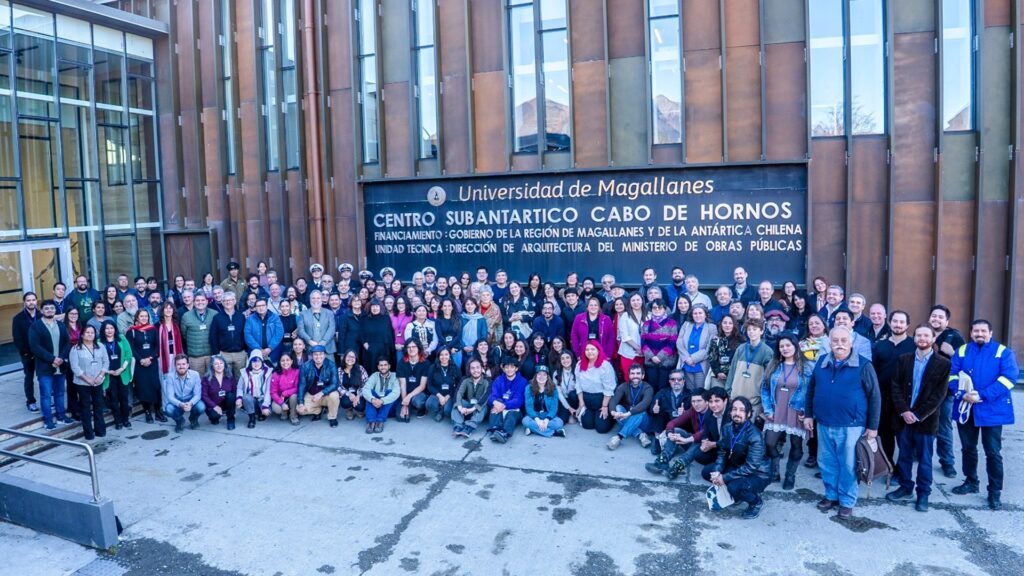 Foto de un grupo de personas bajo un letrero que dice Universidad de Magallanes, Centro Subantártico Cabo de Hornos.