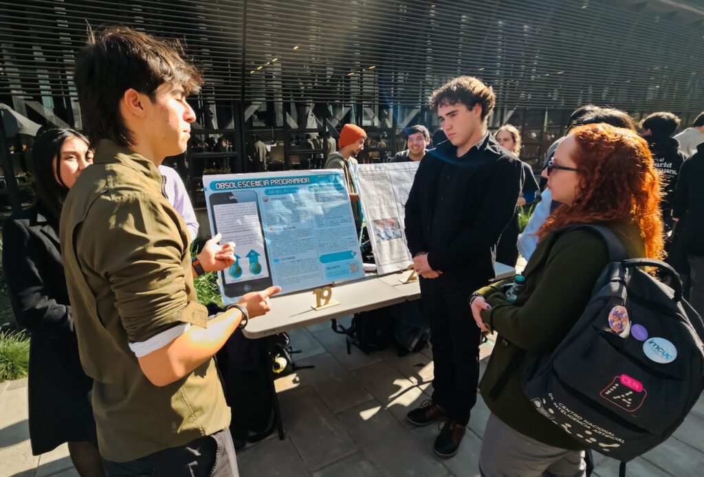 Foto de la académica del IEA UC, Gabriela Arriagada, evaluando el trabajo de los estudiantes del curso Ética para Ingeniería en la Feria de Pósters.