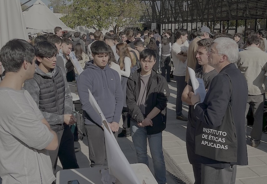 Foto de la académico del DCC UC, Yadran Eterovic, evaluando el trabajo de los estudiantes del curso Ética para Ingeniería en la Feria de Pósters.
