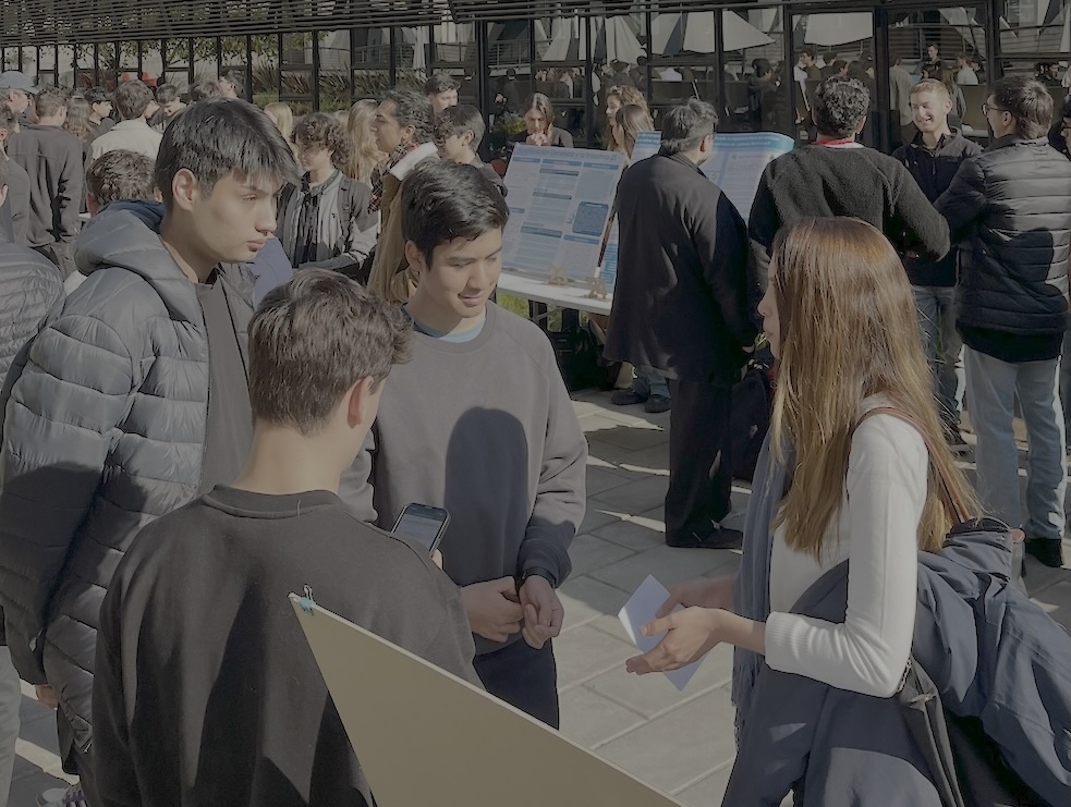 Foto de la académica del IEA UC, Constanza Guajardo, evaluando el trabajo de los estudiantes del curso Ética para Ingeniería en la Feria de Pósters.