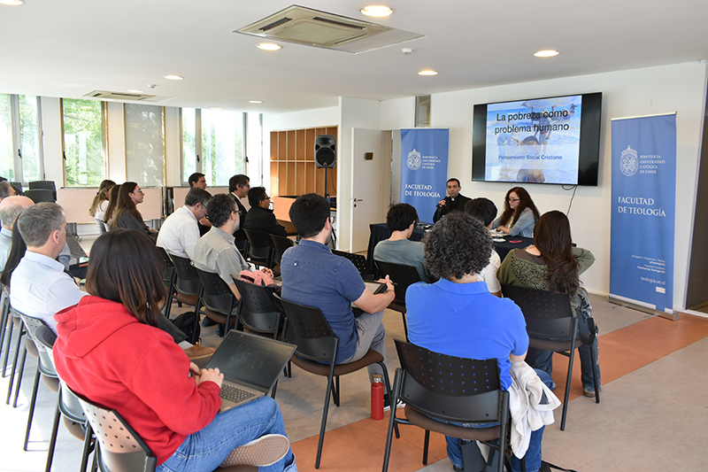 Foto del académico Cristian Mendoza y la académica Alejandra Marinovic en la conferencia “La pobreza como problema humano: Relaciones de escasez entre bienes materiales, racionales y espirituales” junto a los asistentes.