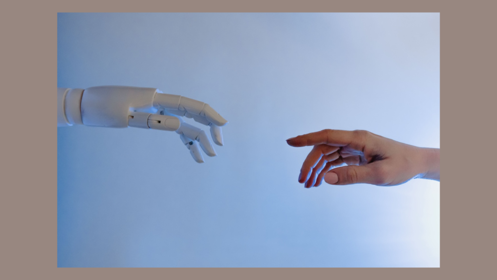 Gráfica con el fondo naranja apagado y en el centro la imagen de dos manos, una a la izquierda que es de un robot y la de la derecha es de humano, y se están acercando para tocarse.